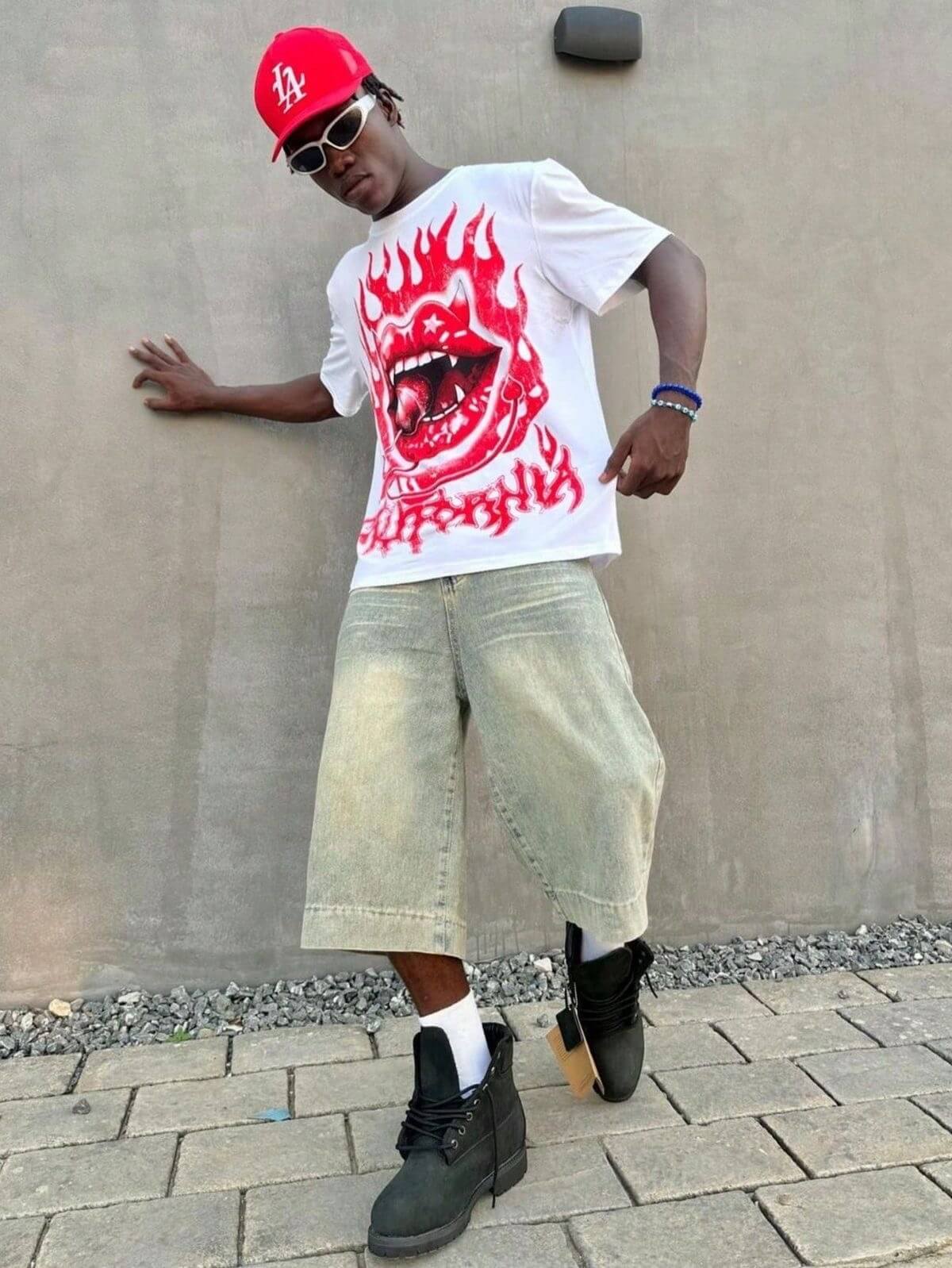 Man in white t-shirt with red flame graphic and cropped denim shorts.