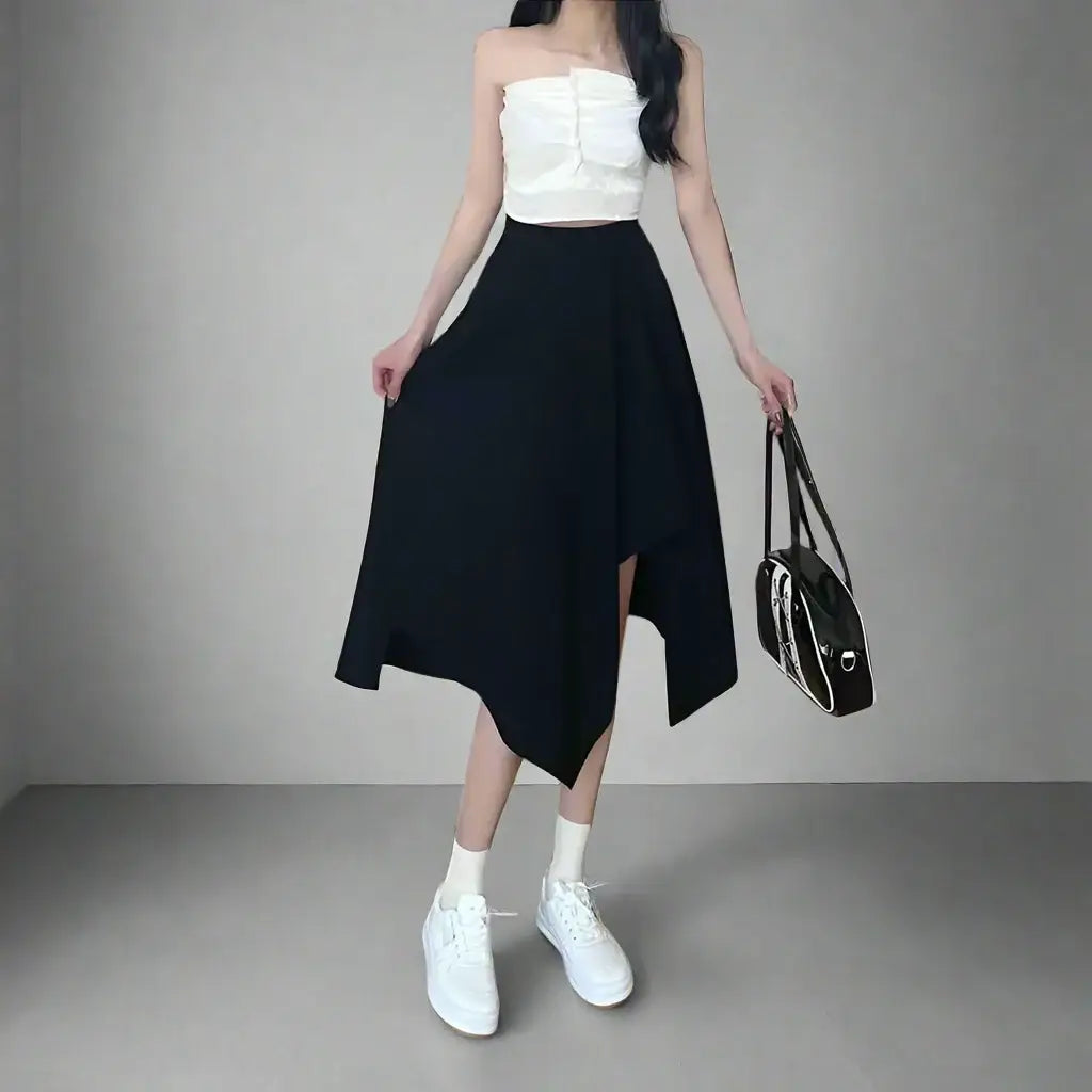 Woman in white crop top and black asymmetrical wrap skirt with white sneakers and handbag