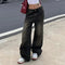 Wide-leg black baggy jeans paired with stylish white sneakers for a trendy look