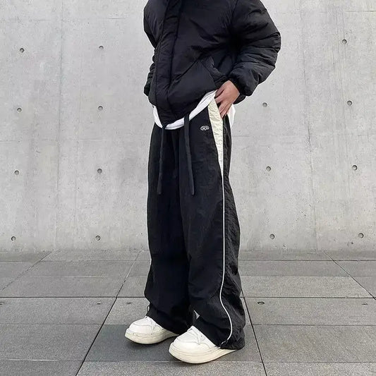 Black baggy pants with white side stripes and drawstring waist for casual style