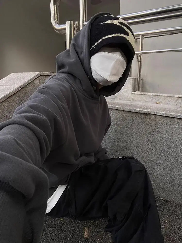 Person in a dark hoodie and white mask wearing a stylish black beanie as Y2K accessories