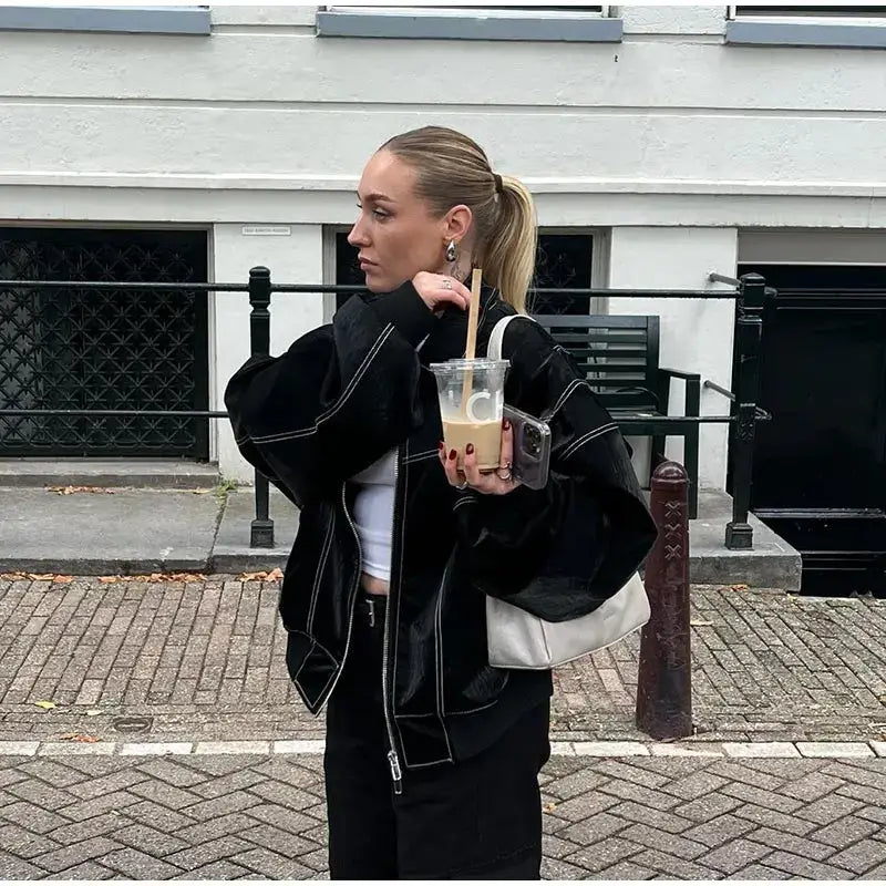 Woman in a black denim jacket enjoying a bubble tea drink