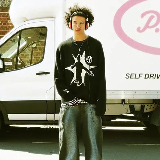 Young man in black knit sweater with graphic design standing by white van