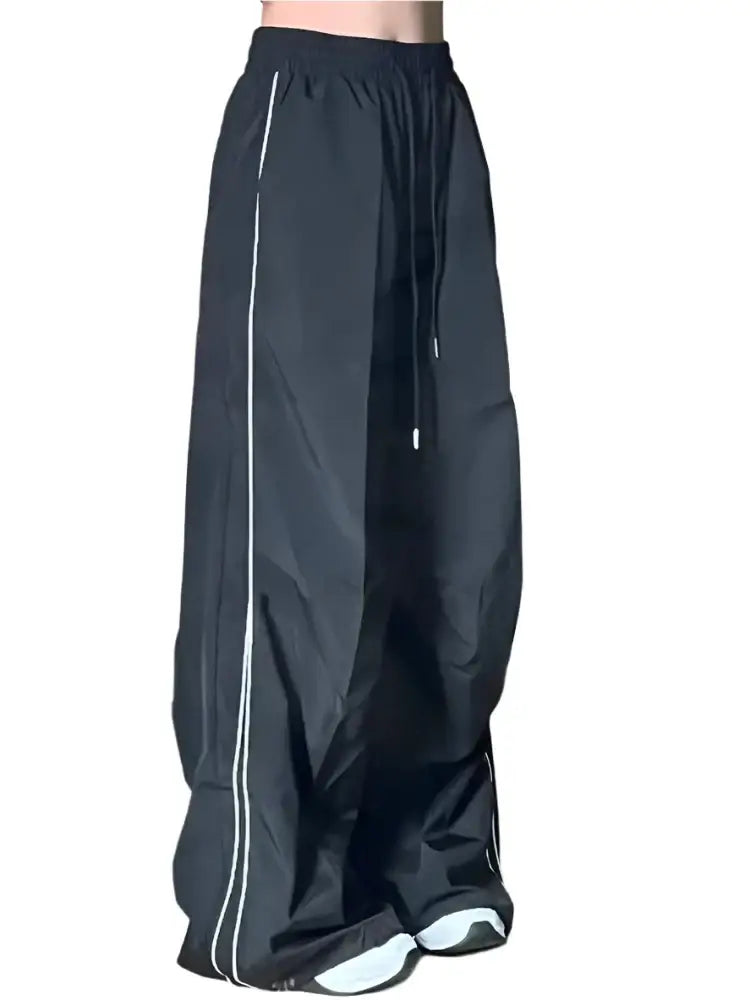 Wide-leg black parachute pants with white side stripes for athletic style and comfort