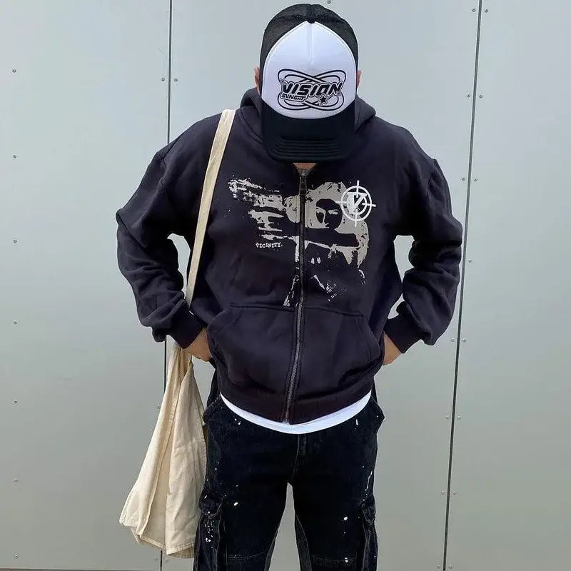 Person in a black Y2K hoodie and white cap carrying a tote bag, showcasing style