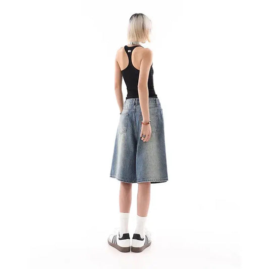 Woman in black tank top and wide-leg denim culottes showcasing blue jorts style