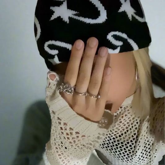 Hand in multiple rings wearing C-Star Beanie with star and moon patterns to stay warm