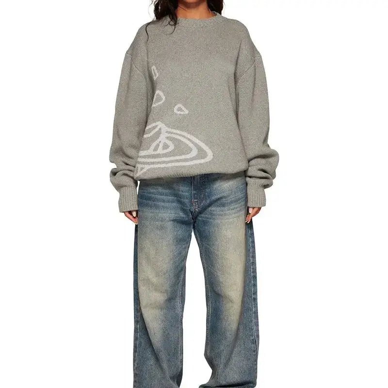 Oversized gray Cosmic Knit Sweater with white abstract design over blue jeans