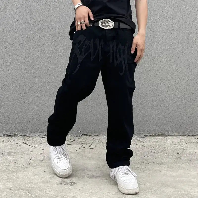 Custom black jeans featured with baggy fit, visible belt buckle, and white sneakers