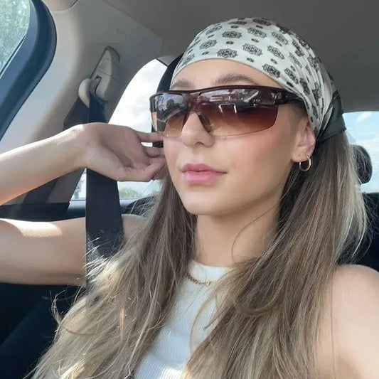 Woman in sunglasses fashion and a patterned headscarf inside a car with cycling sunglasses