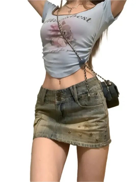 Woman in cropped white t-shirt and short dark washed mini skirt with a small handbag