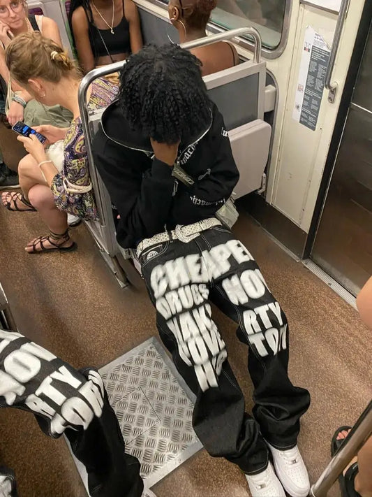 Person wearing Drip Jeans with bold text on black background on subway train