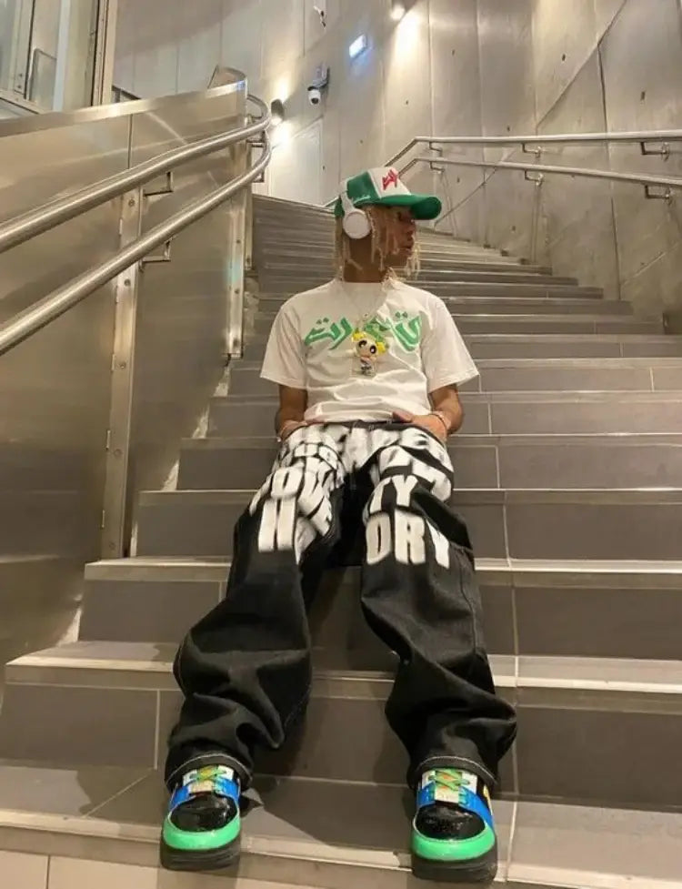 Person sitting on stairs in oversized pants and a graphic tee, showcasing Y2K Drip Jeans