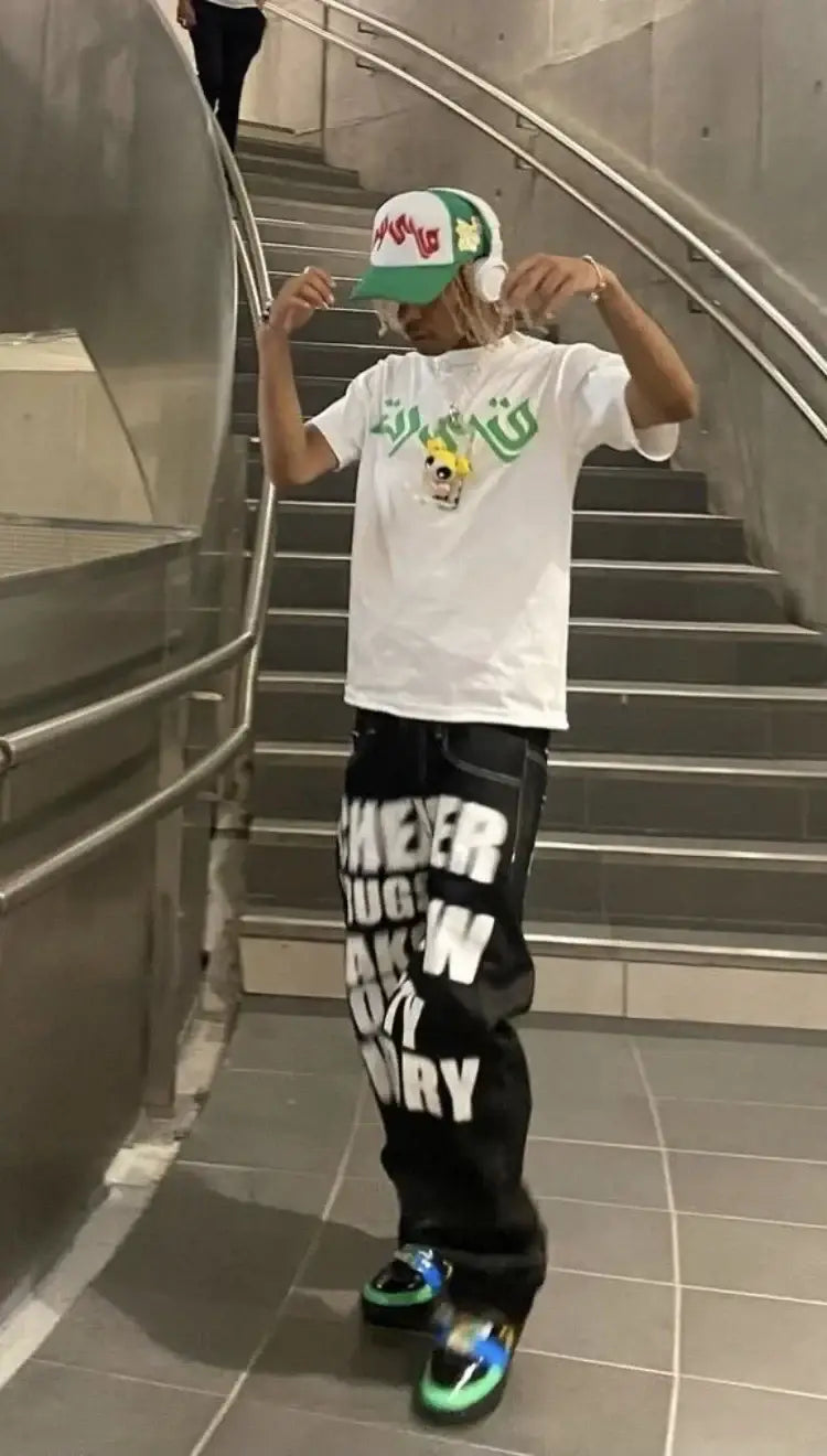 Person in white t-shirt and cap showcasing stylish Y2K drip jeans on stairs