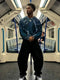 Young man in blue drip sweater and black pants inside a subway car, Y2K style