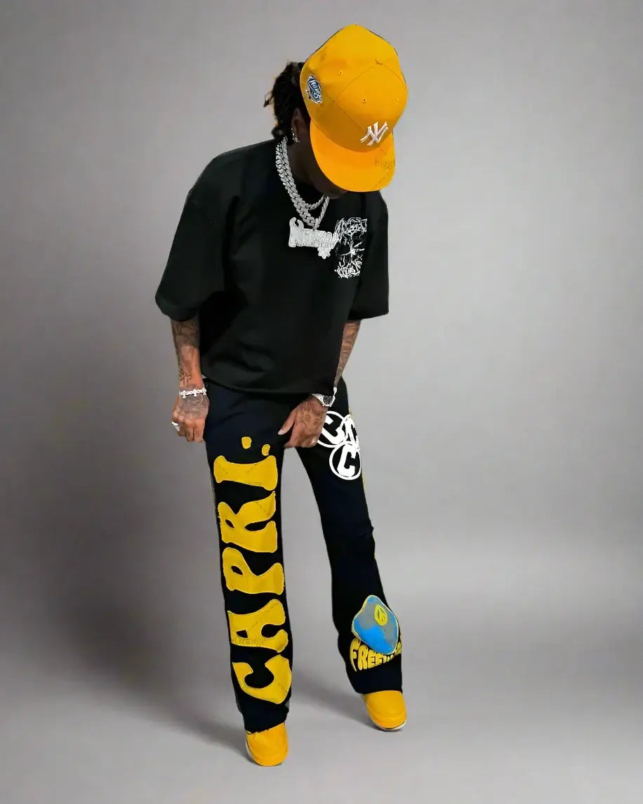 Person in bright yellow cap and colorful pants showcasing Embroidered Sweatpants Y2K style