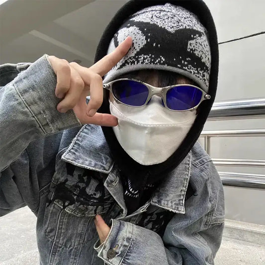 Person in a fashion beanie, denim jacket and sunglasses making a peace sign gesture