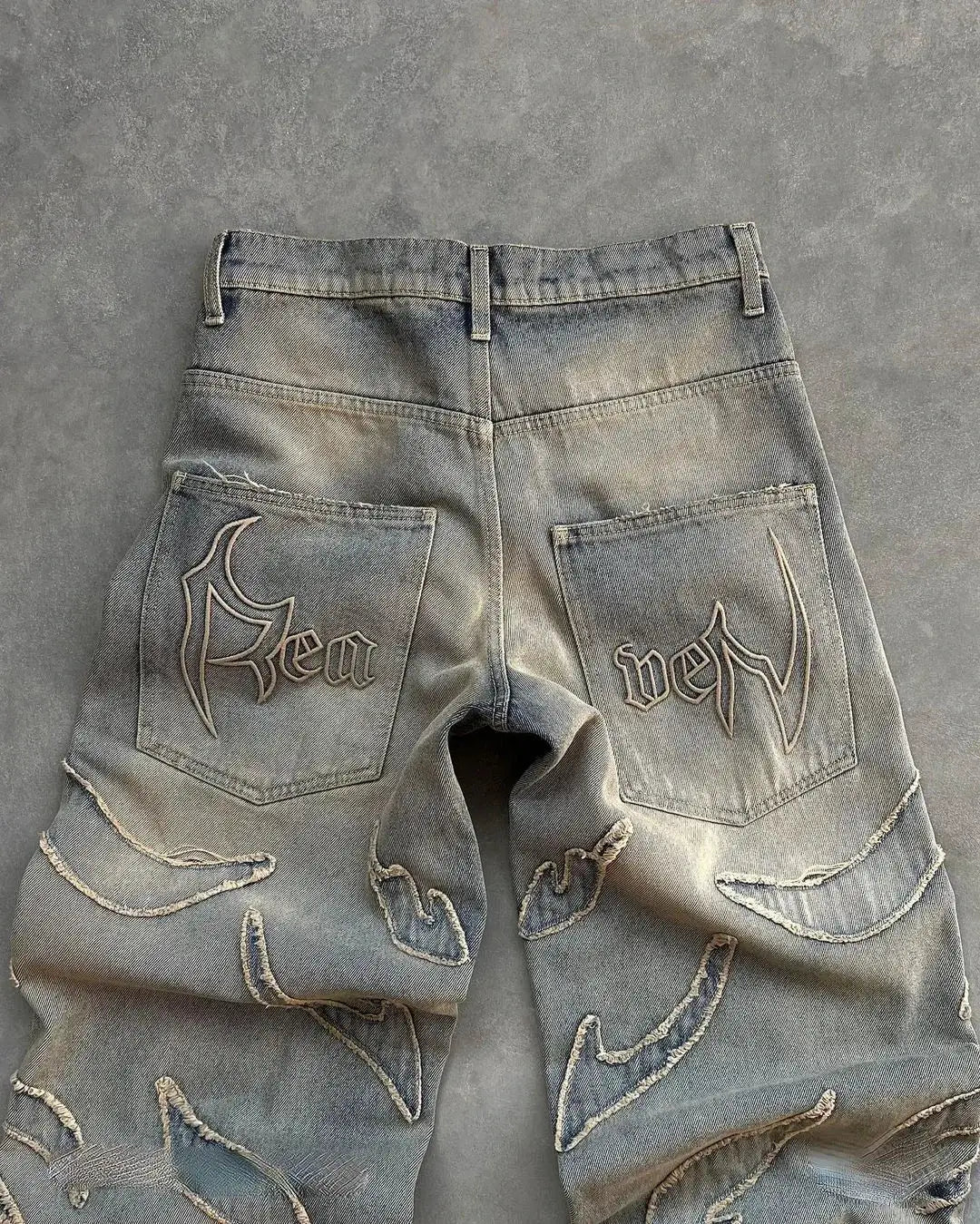 Distressed gray Y2K jeans with embroidered designs on pockets and legs, wide leg style