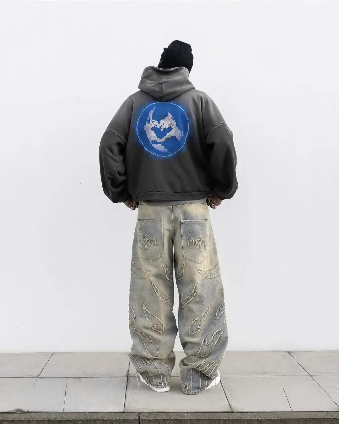 Person in gray hoodie and baggy light-colored Y2K jeans with blue logo