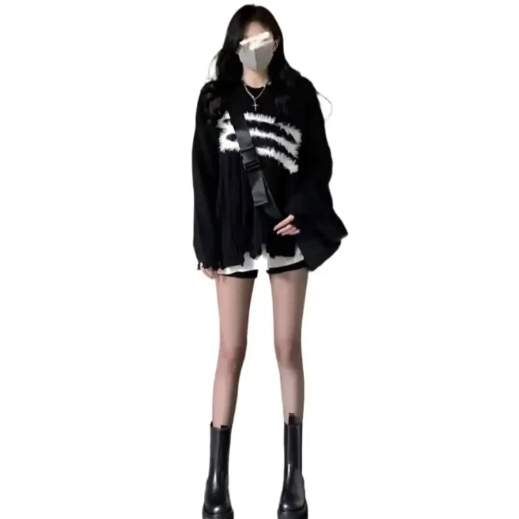 Person in a black oversized Harajuku sweater, shorts, and knee-high boots, trendy Y2K style