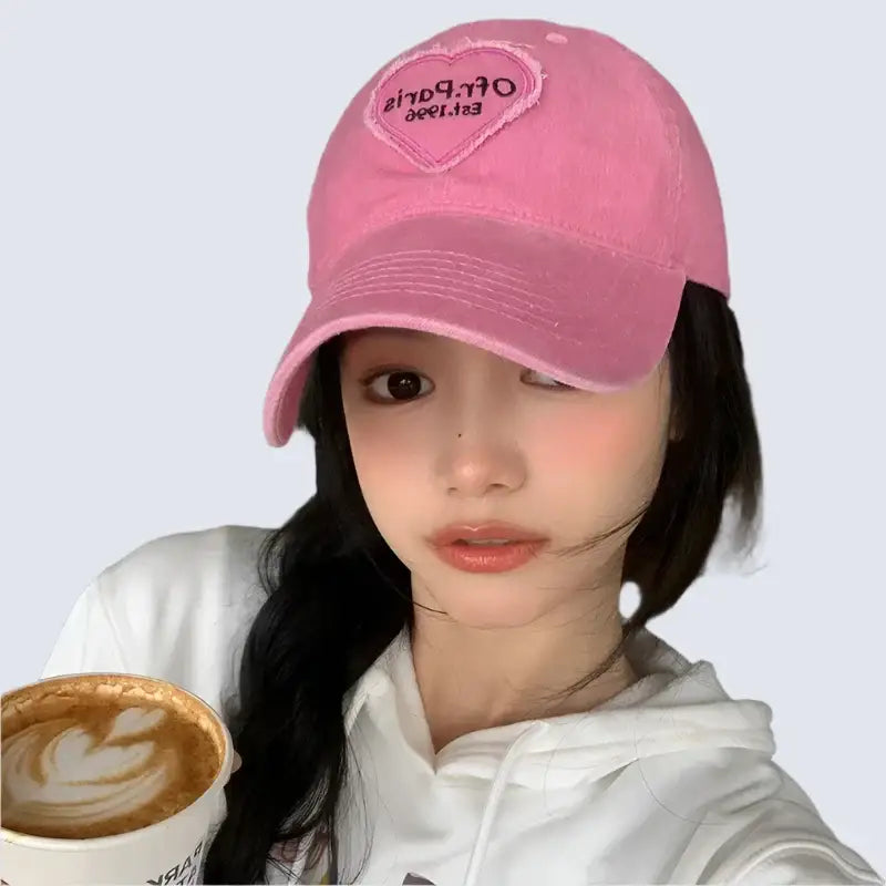 Young woman in a pink Heart Cap holding a latte art coffee cup, trendy Y2K accessories