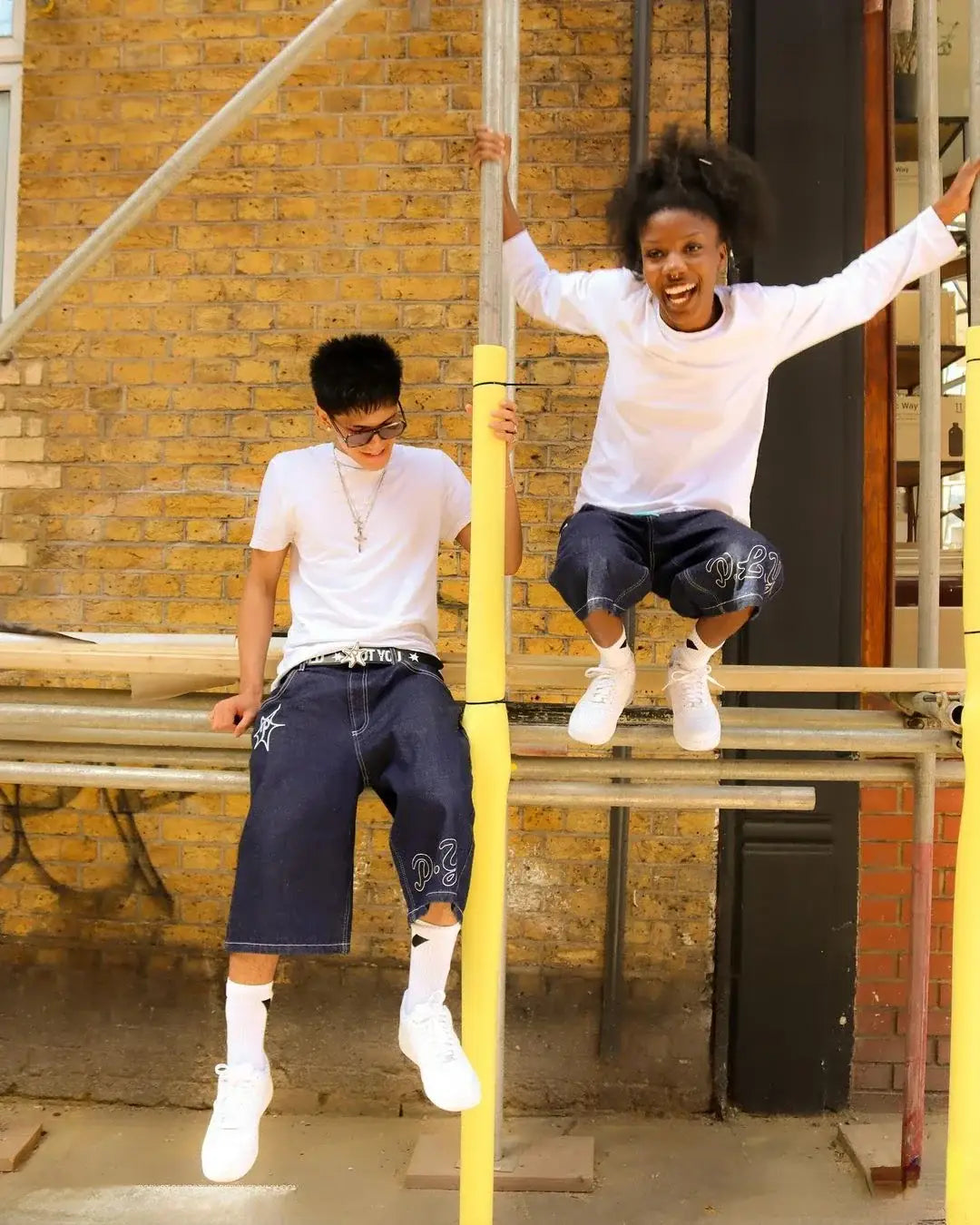 Two children playing on scaffolding in Hip Hop Shorts outside a brick building