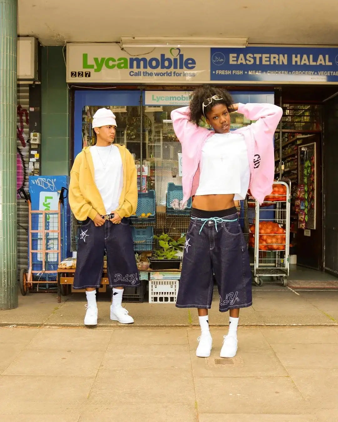 Two young men in hip hop shorts standing outside a mobile phone shop