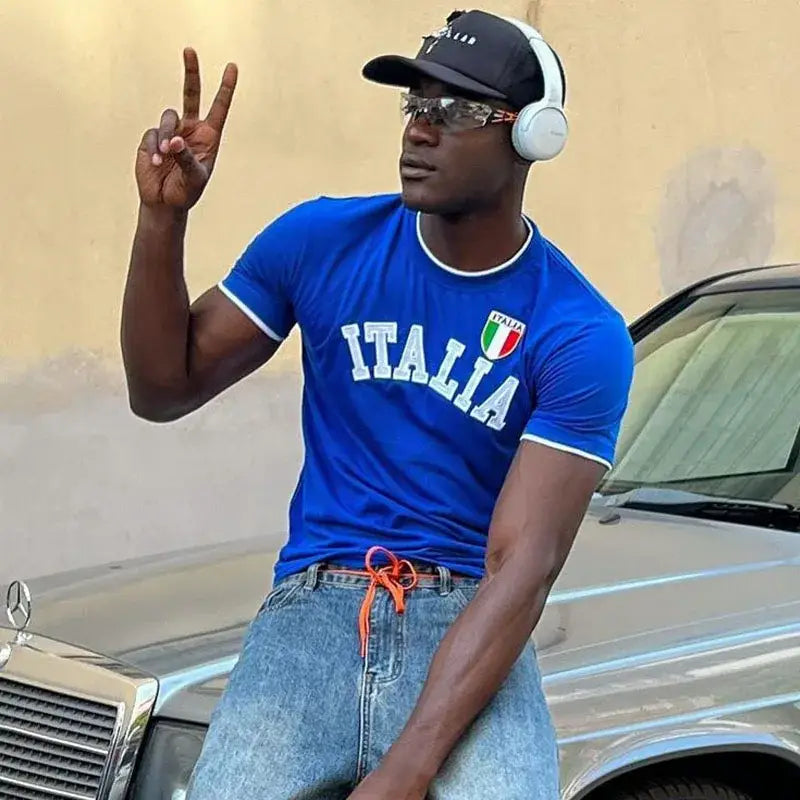 Man in blue Italia T Shirt making peace sign gesture, showcasing unparalleled comfort