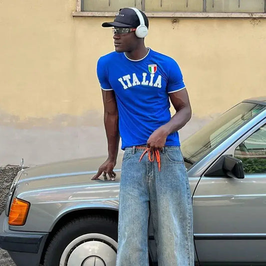 Man in blue Italia T Shirt and jeans near car, showcasing Y2K style and unparalleled comfort