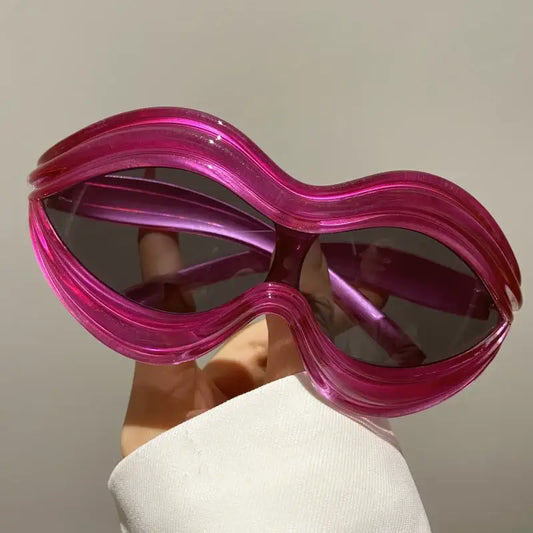 Bright pink oversized lip sunglasses with a wavy shape, perfect for Y2K fashion