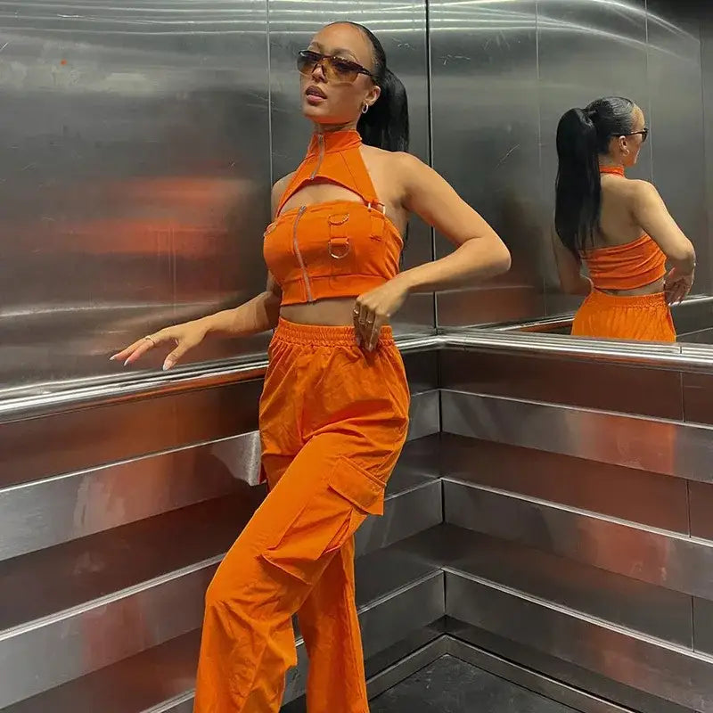 Woman in bright orange cargo pants and crop top showcasing stylish summer fashion