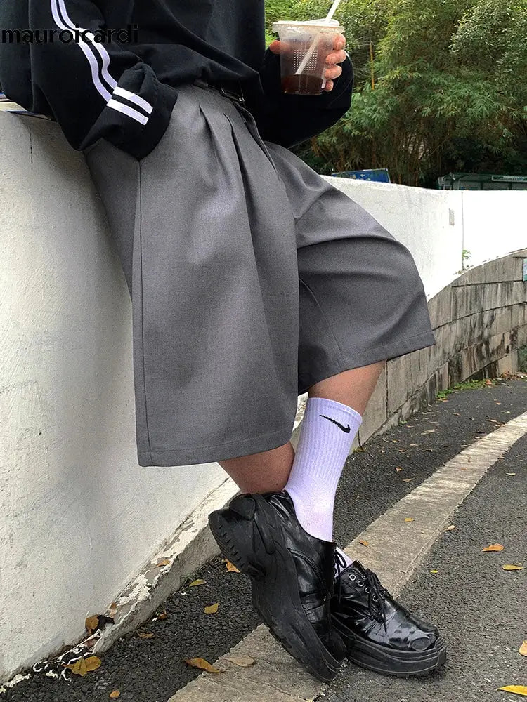 Gray pleated skirt paired with black shoes and lavender socks styled with oversized jean shorts