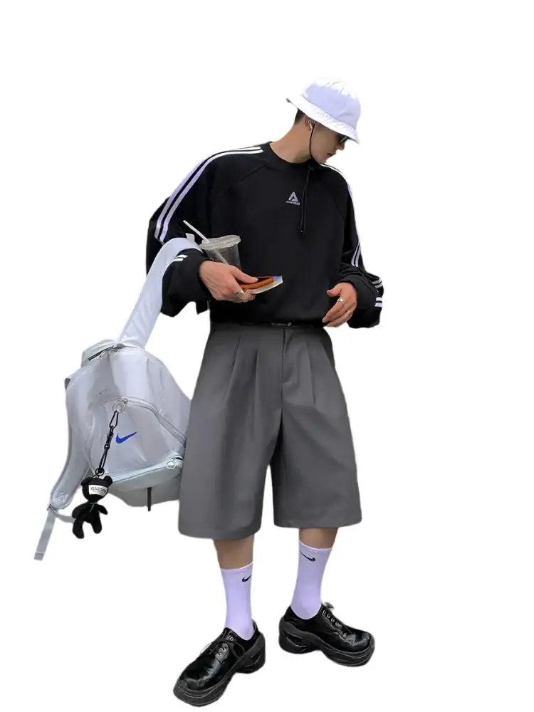 Person in black Adidas sweatshirt and oversized jean shorts with a white bag