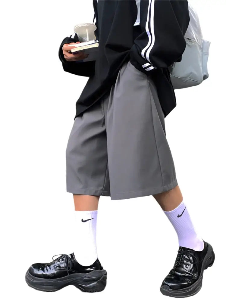 Person in gray skirt, black jacket, and purple socks styling oversized jean shorts