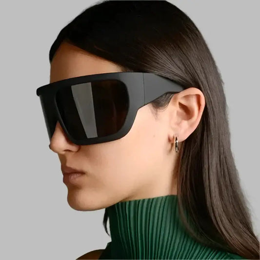 Oversized sunglasses with wide shield-like lens worn by person with long dark hair