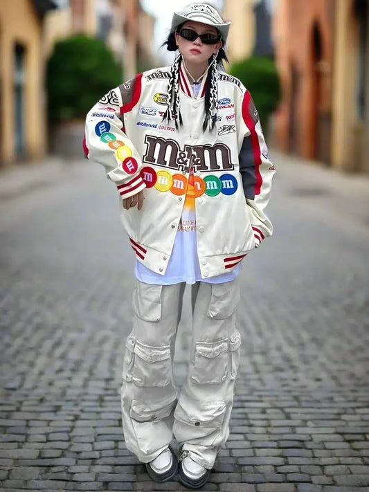 Person in a white M&M’s Patch Moto Jacket and baggy pants on cobblestone street