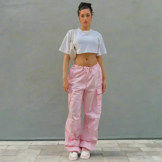 Woman in a white crop top and pink cargo pants showcasing trendy fashion style