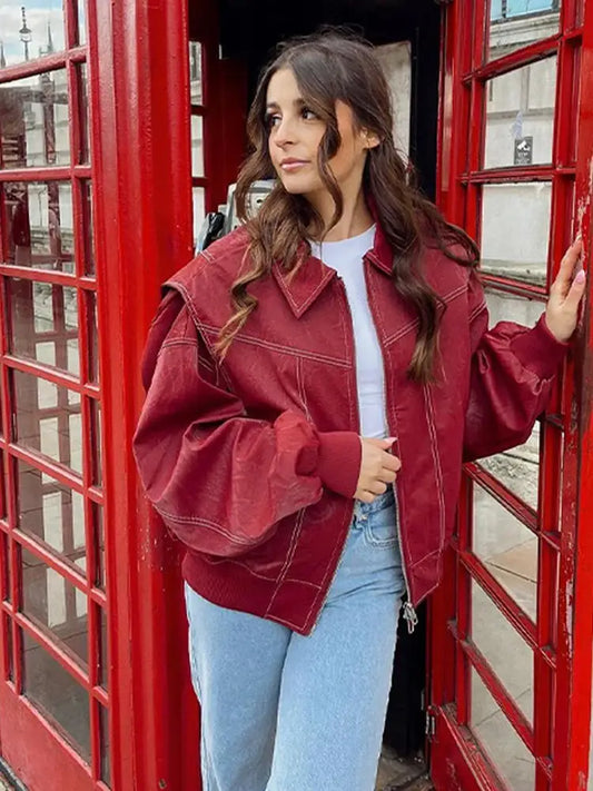 Woman in a burgundy leather jacket posing next to a red phone booth wearing a red oversized jacket