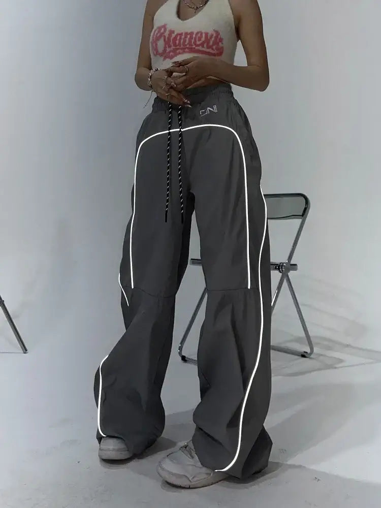 Wide-leg gray reflective parachute pants with white side piping for stylish comfort