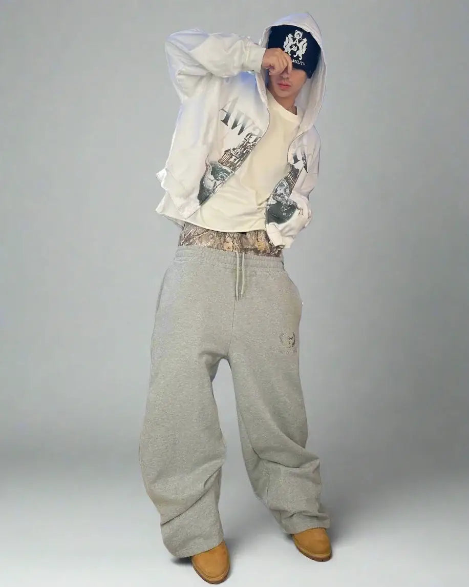 Person in baggy retro sweatpants, white jacket, and dark headband, embodying Y2K style