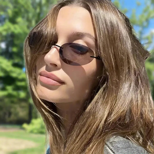 Woman with long brown hair wearing rimless sunglasses outdoors with stylish Y2K flair