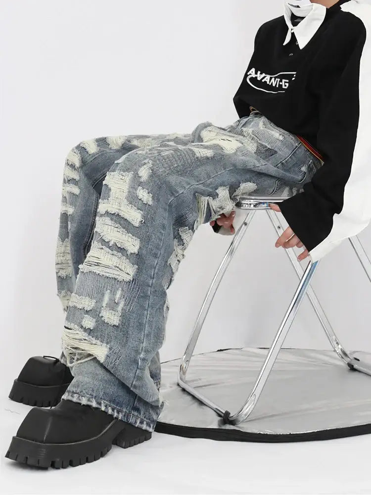 Distressed camouflage-patterned ripped jeans for men worn by a seated person