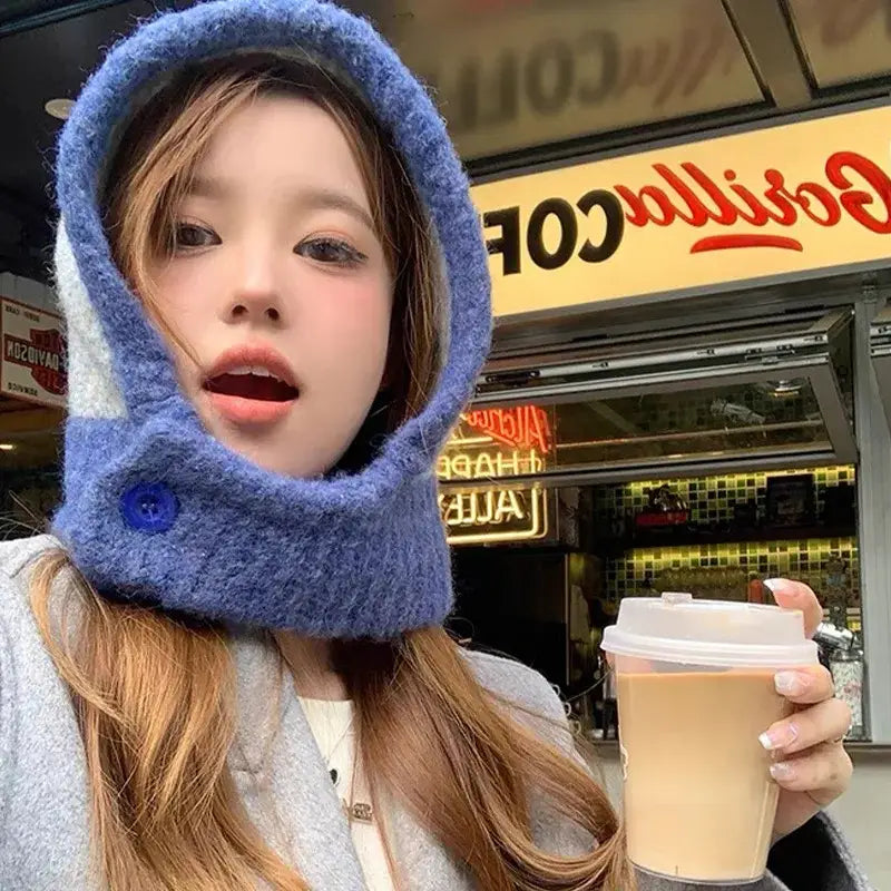 Young woman in a blue cotton blend scarf balaclava holding a coffee cup outdoors