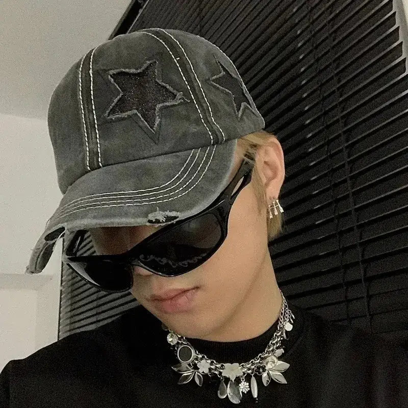 Distressed gray Star Cap with star designs worn by a person in sunglasses and necklace