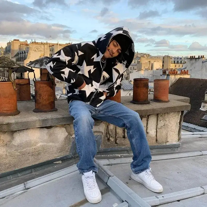 Person in a star hoodie Y2K sitting on a rooftop ledge, showcasing stylish urban fashion