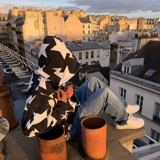 Person in a star hoodie Y2K sitting on a rooftop, embracing Y2K fashion trends