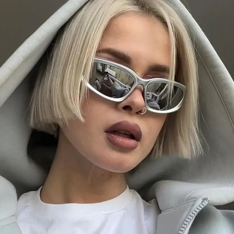 Woman with platinum blonde hair wearing streetwear sunglasses and a white top