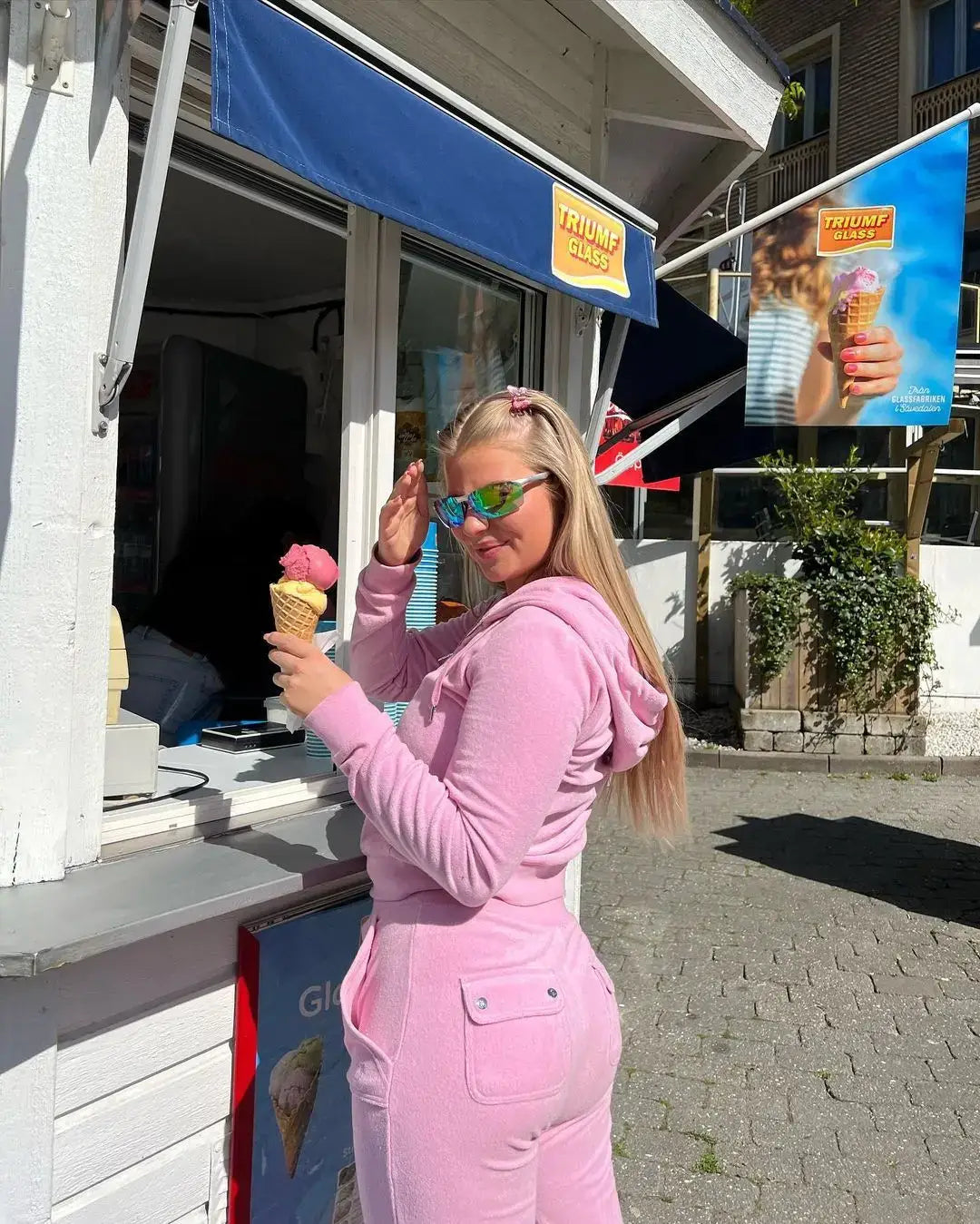 Woman in a pink velour sweat outfit enjoying an ice cream cone outdoors