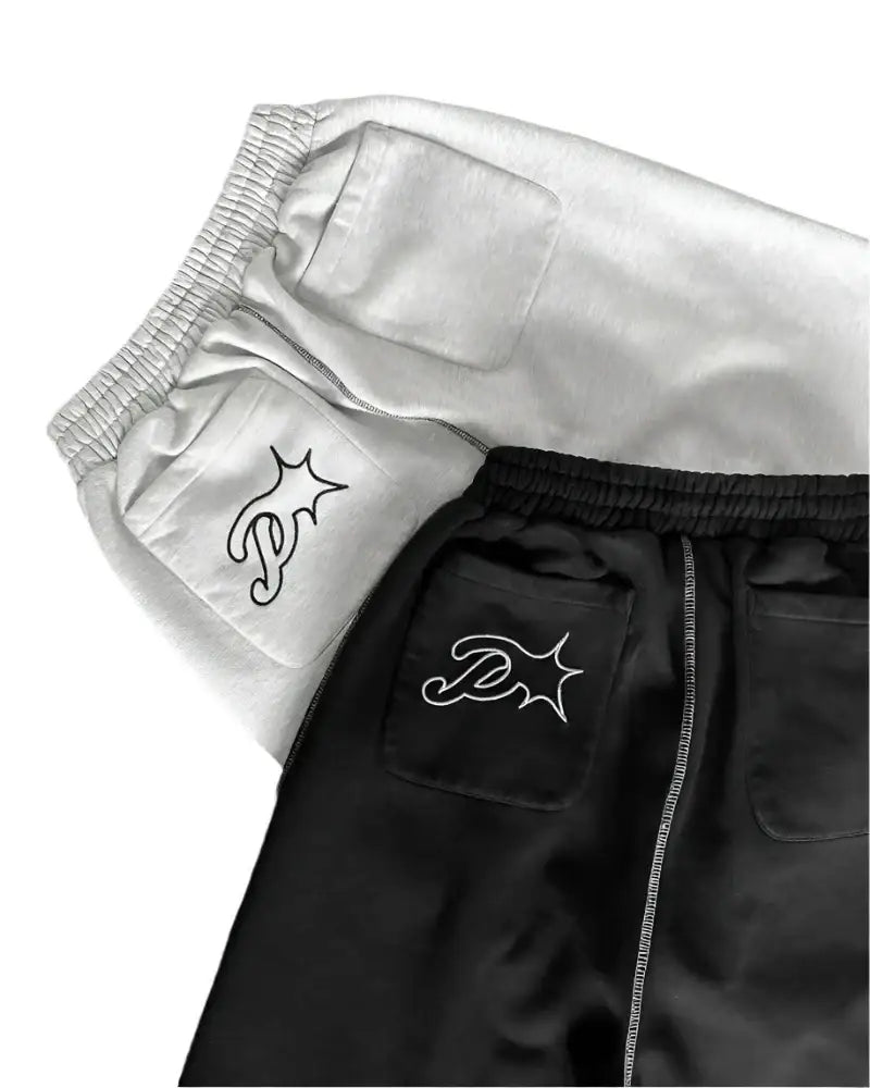 Pair of black and white wide leg sweatpants with embroidered star designs on pockets