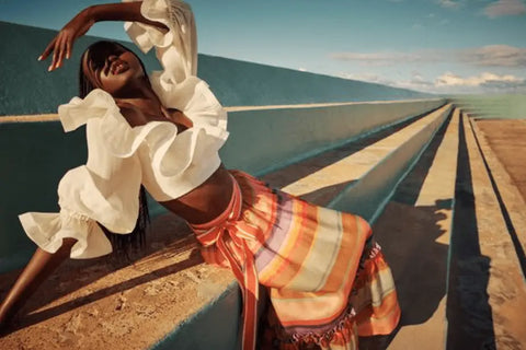 Woman in a flowing white top and colorful skirt embodying Y2K fashion on a road.